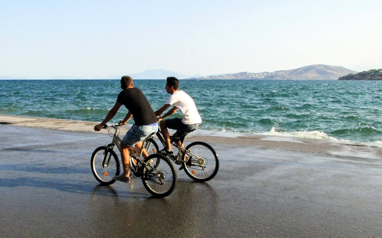 Twee mannen fietsen langs de zee op de boulevard